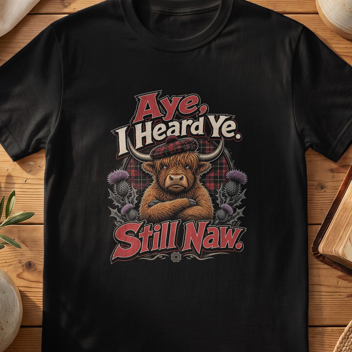 Black Gildan 64000 unisex T-shirt flatlay with Aye I Heard Ye Still Naw Scottish graphic design