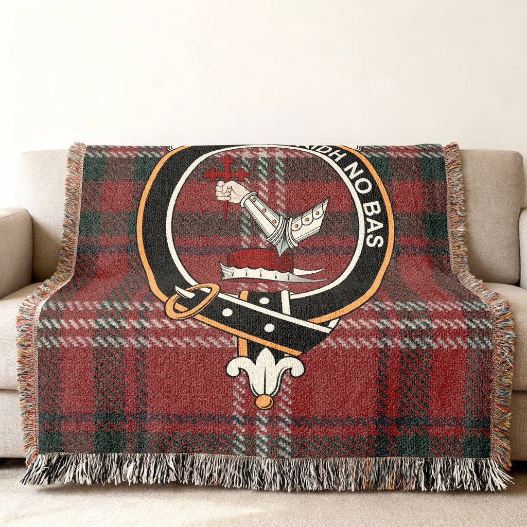 Close view of the MacDougall woven blanket draped over a sofa, showing the crest and fringed edges