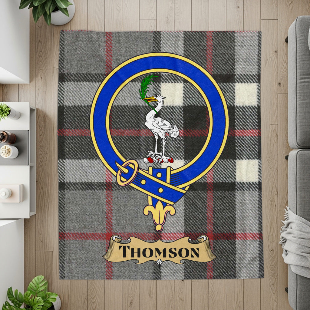 Thomson crest on grey tartan printed throw — flat lay detail