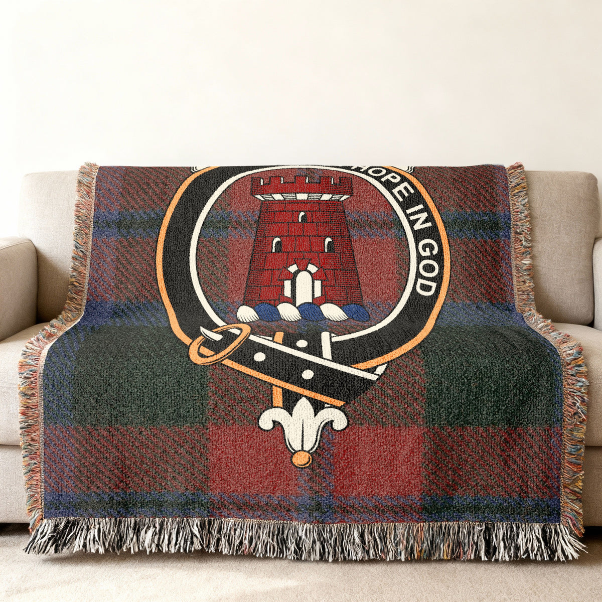 Close view of the MacNaughten woven blanket draped over a sofa, showing the crest and fringed edges