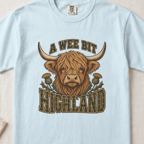 A Wee Bit Highland Highland cow design on a Chambray Comfort Colors 1717 T-shirt, flat lay