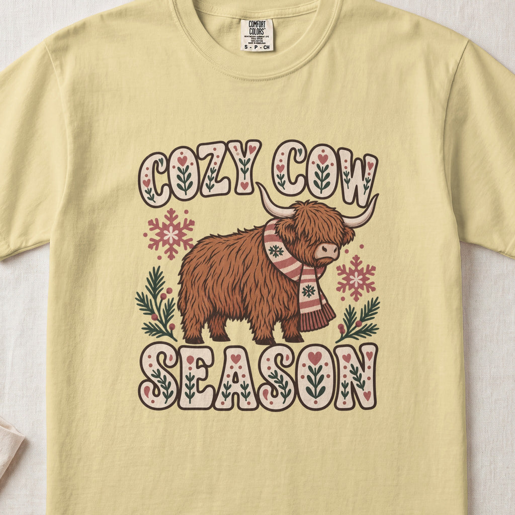 Cozy Cow Season Highland cow design on a Butter Comfort Colors 1717 T-shirt, flat lay