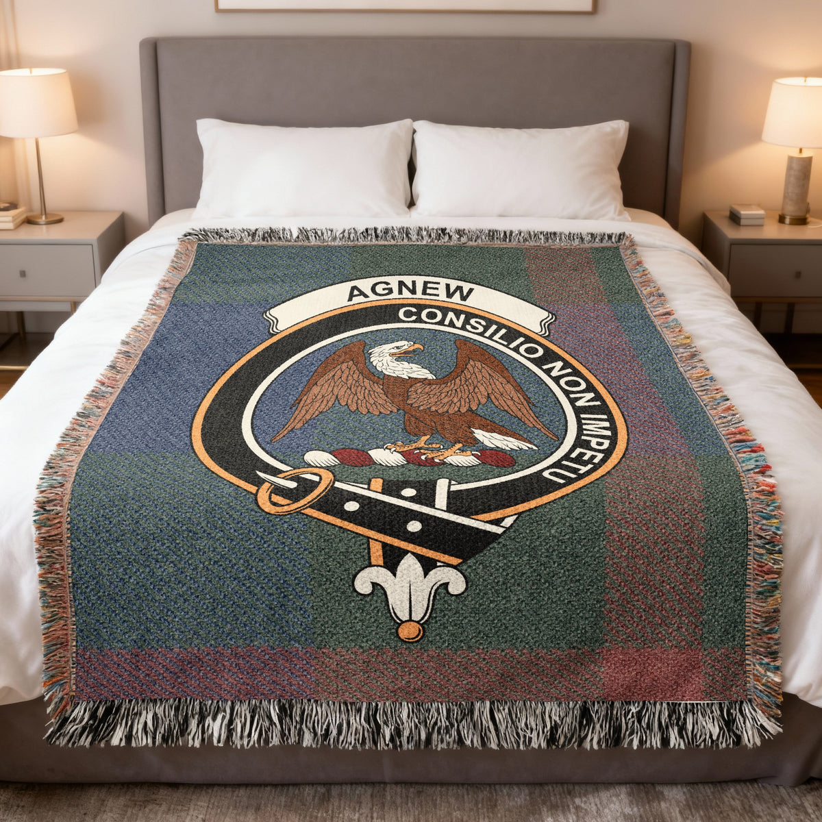 Agnew woven blanket displayed on a bed, with an eagle with outstretched wings on a muted blue, green and red tartan background