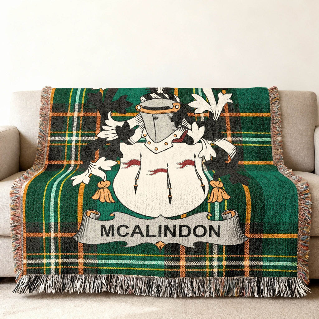 Green tartan throw blanket with MCALINDON crest on a sofa.