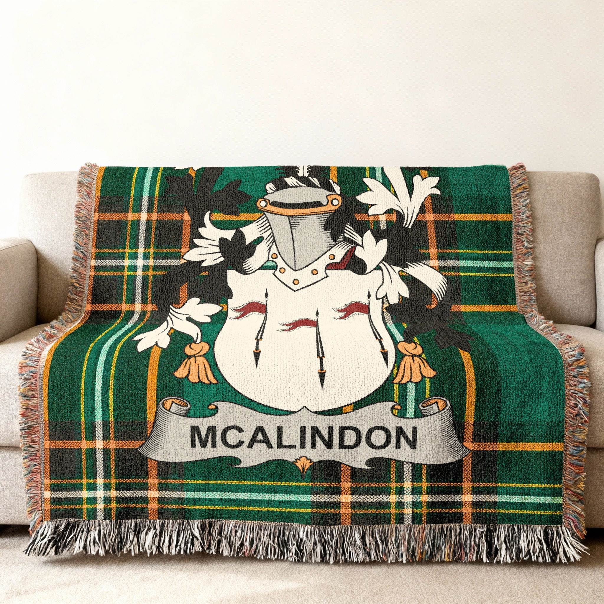 Green tartan throw blanket with MCALINDON crest on a sofa.