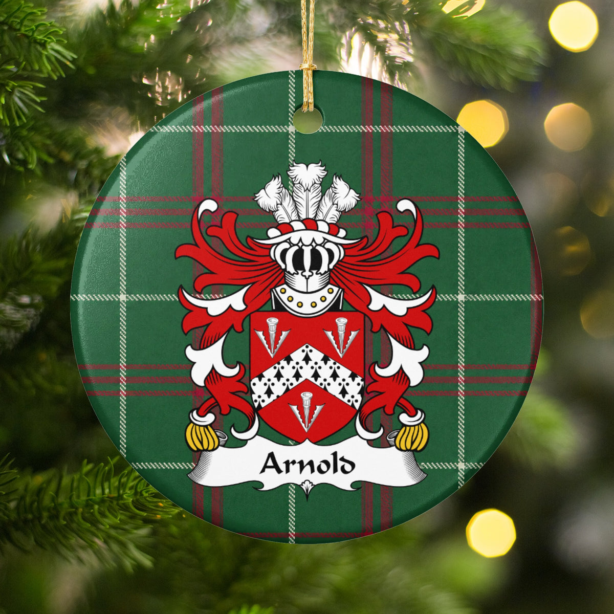 Arnold family crest and surname on a round Welsh national tartan ornament, hanging by a gold cord among Christmas tree branches and warm golden lights.