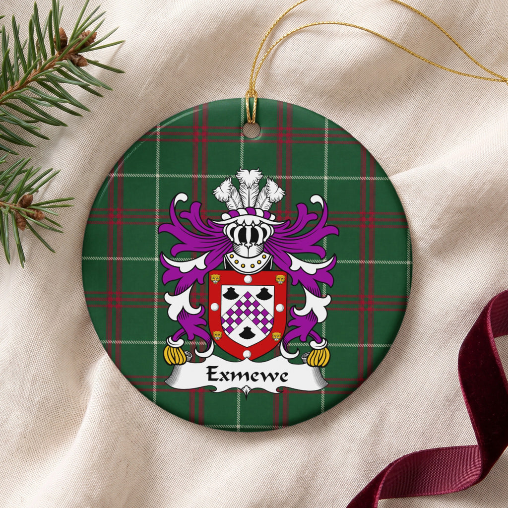 Exmewe ornament on cream fabric beside evergreen and burgundy ribbon; a purple-and-white checked chevron between three black shells, within a red border decorated with white circles and gold animal faces on Welsh national tartan.