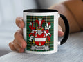 White mug with black handle displaying Alcock family crest on tartan background.
