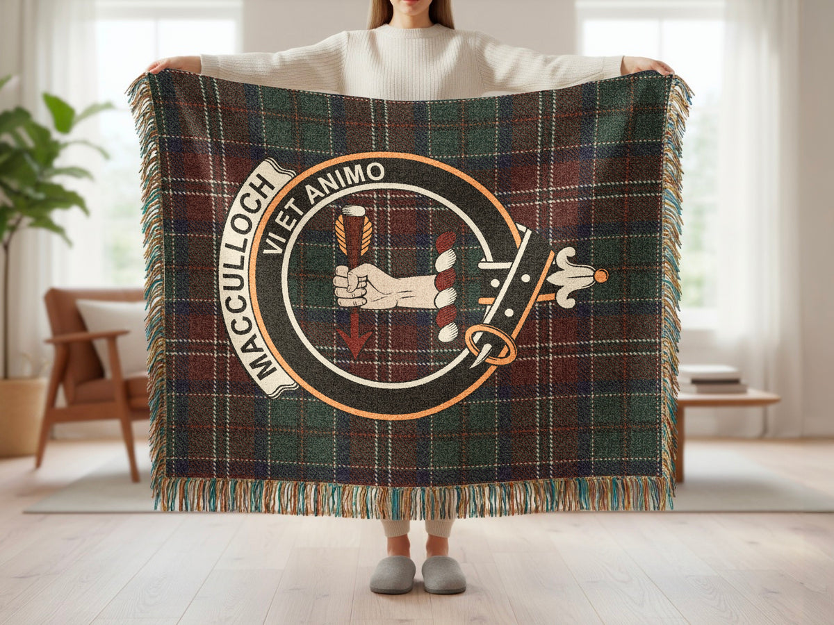 Person holding the MacCulloch woven blanket to show the full design, tartan background and fringe