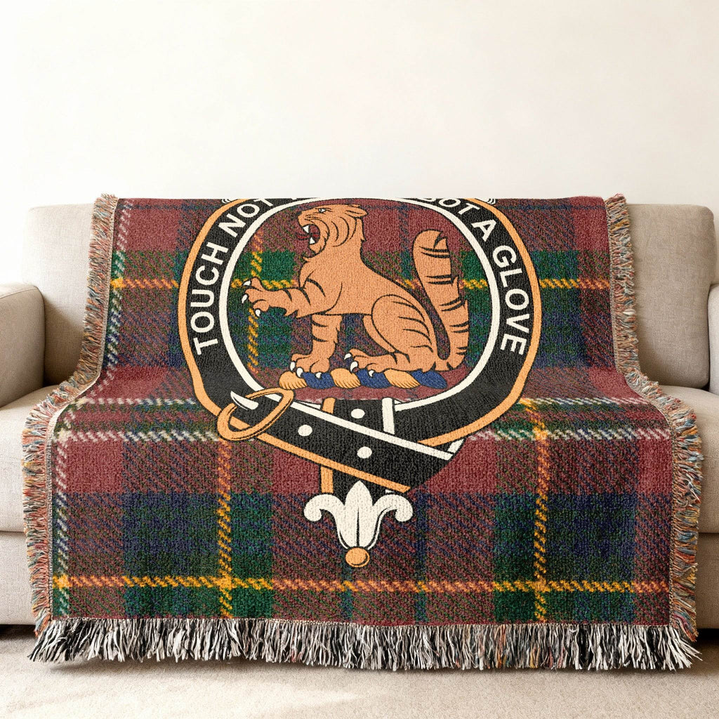MacPherson clan crest woven blanket draped over sofa — Touch Not The Cat tartan cotton throw