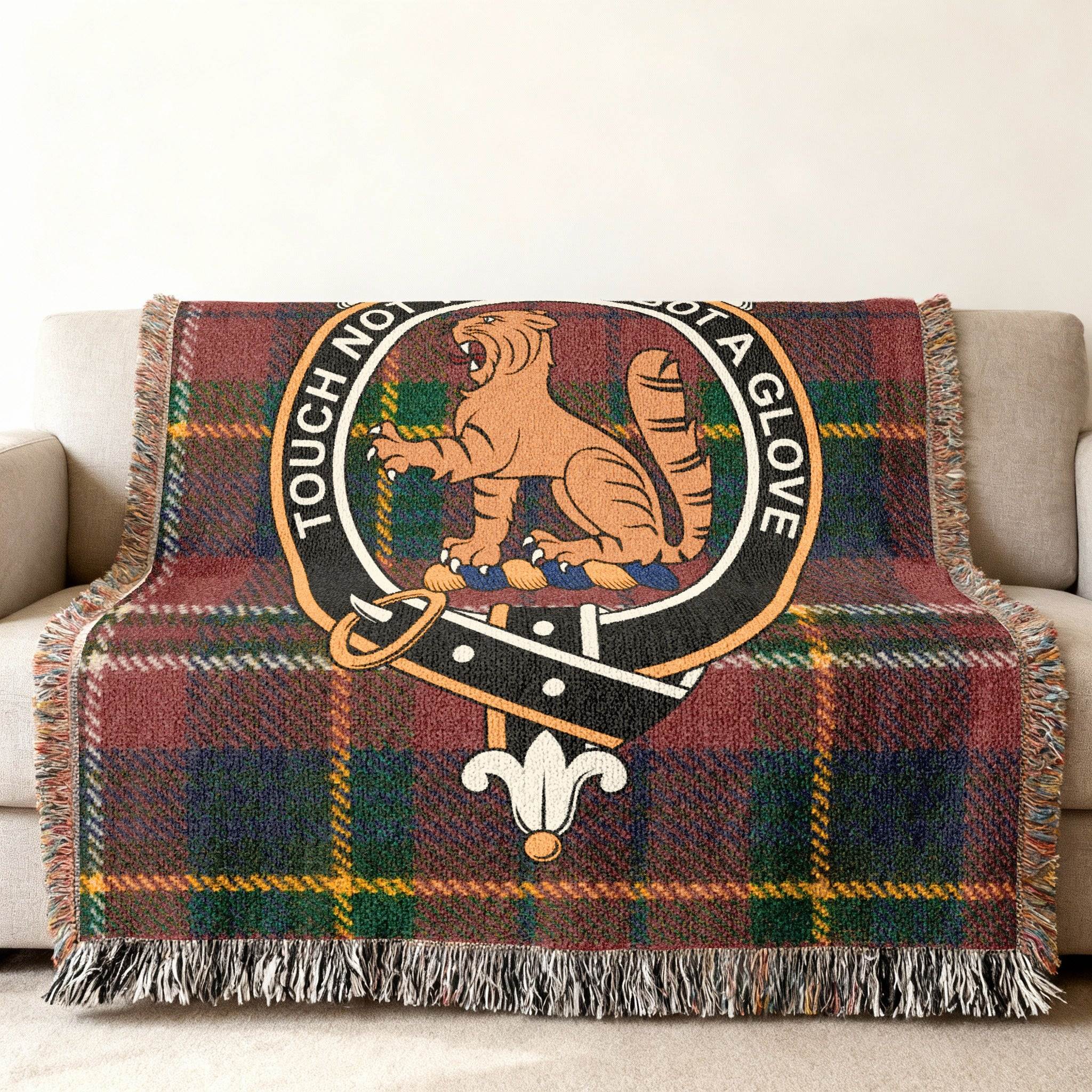 MacPherson clan crest woven blanket draped over sofa — Touch Not The Cat tartan cotton throw