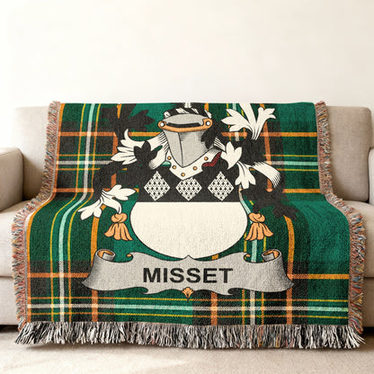 Green tartan blanket with Misset family crest on a sofa.