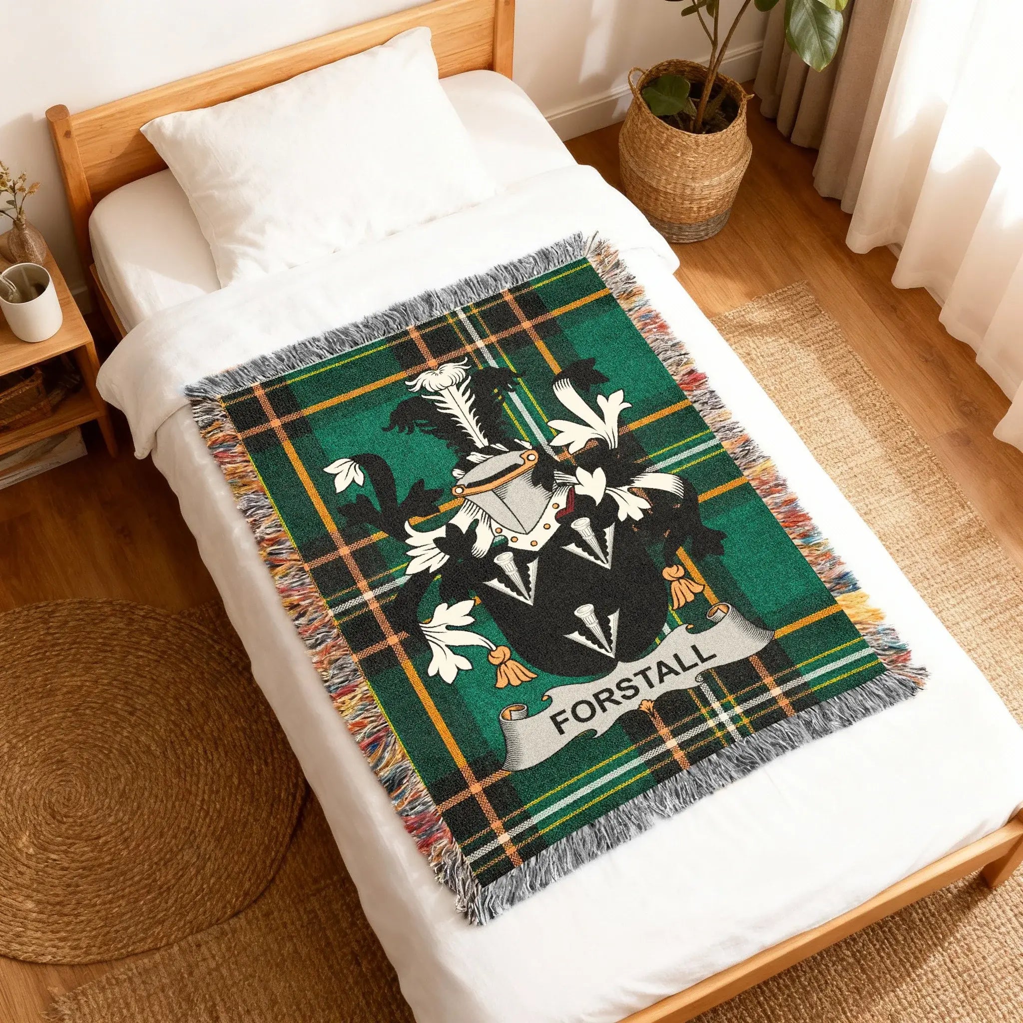 Green tartan blanket with crest and "FORSTALL" text on a white bed.