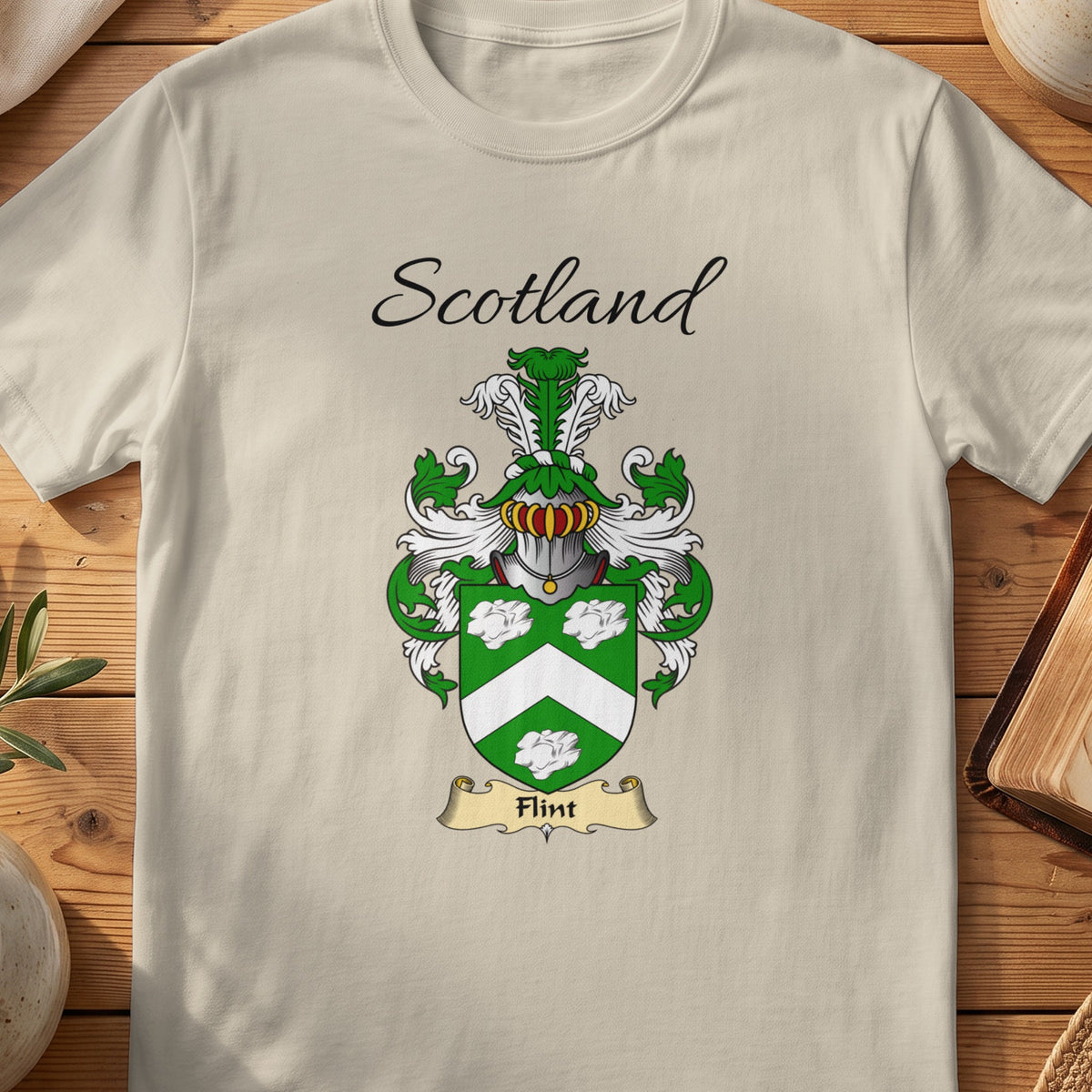 Sand Flint Scottish family shield T-shirt featuring a white chevron and decorative motifs on green