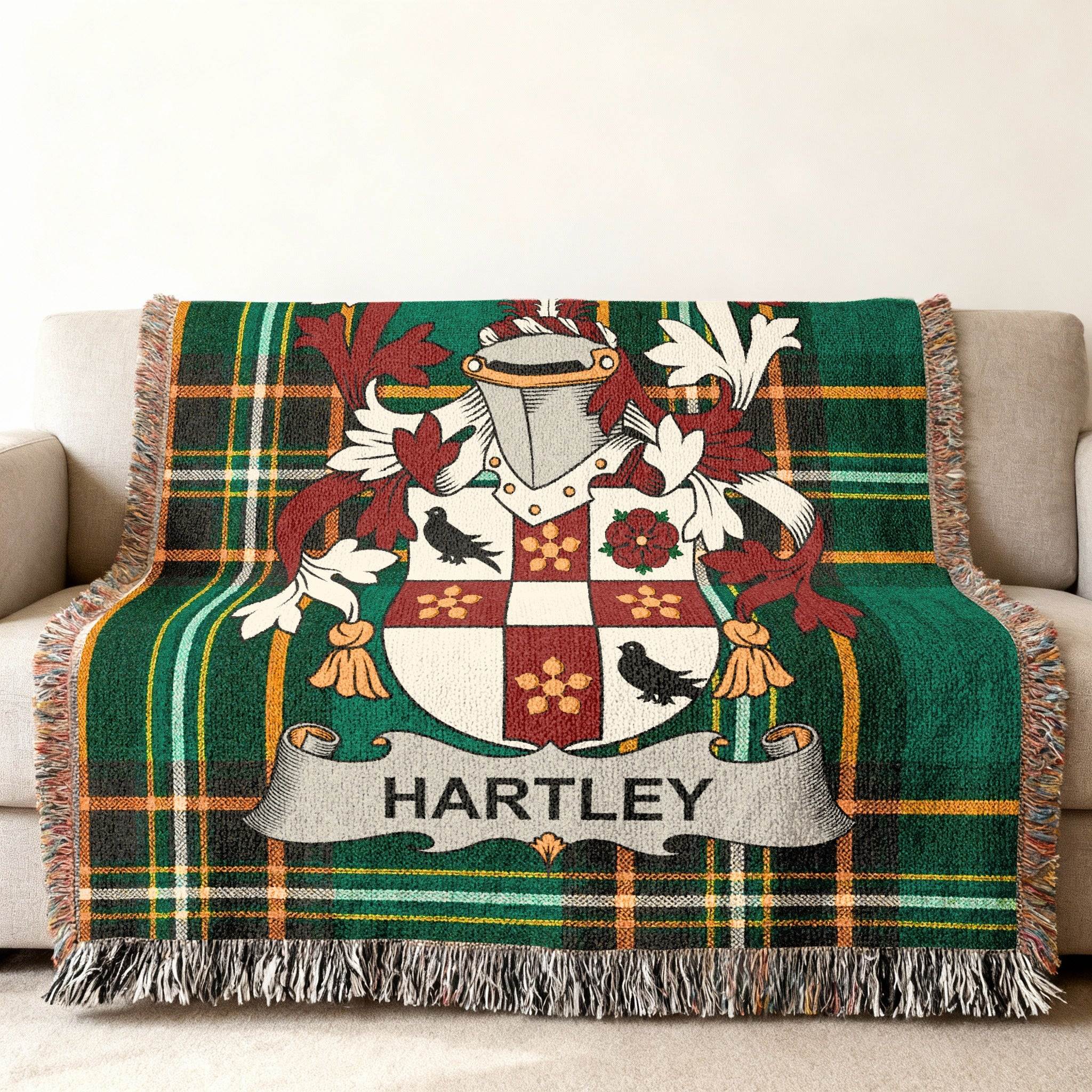Green plaid blanket with Hartley family crest draped on a sofa.
