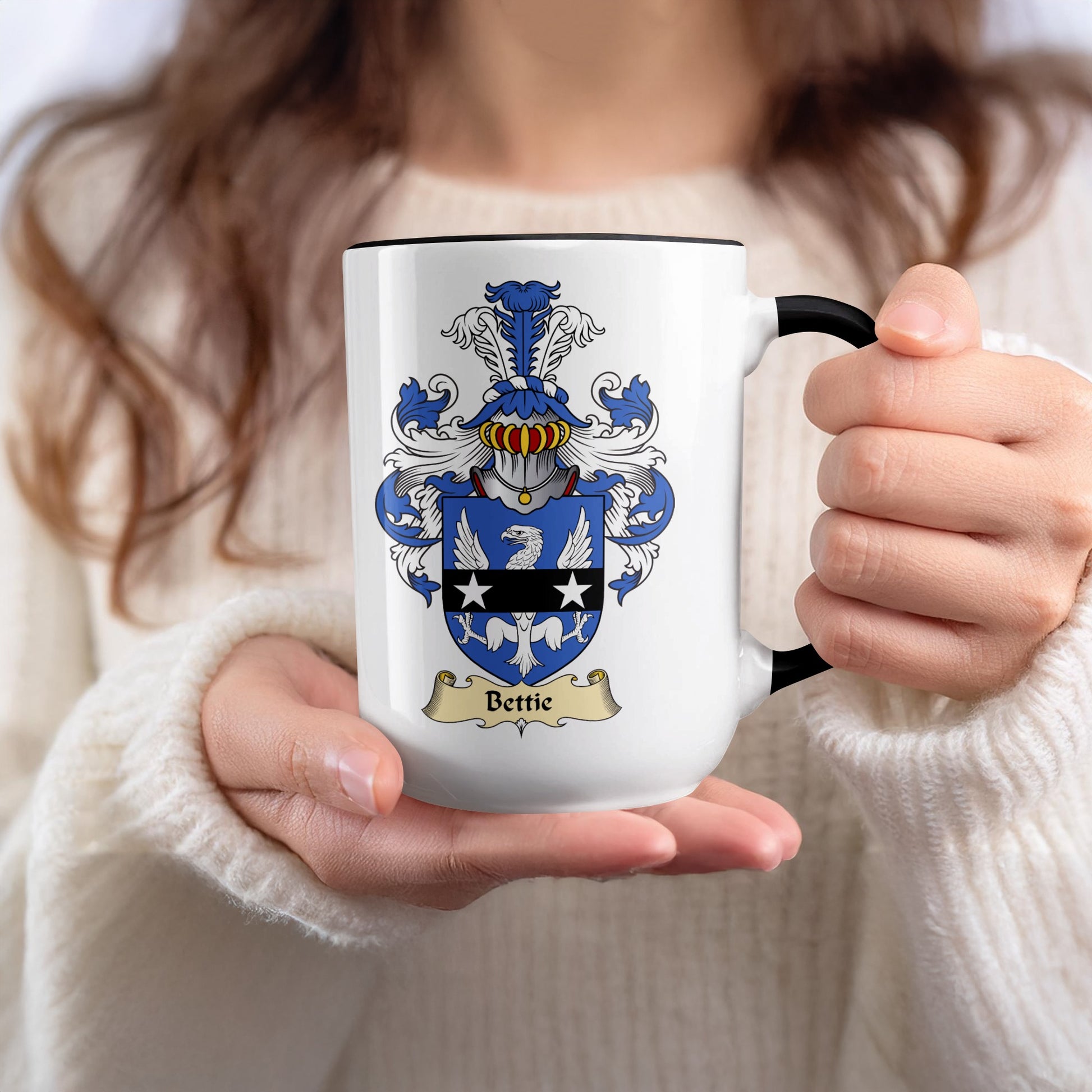 White mug with black rim, featuring the Bettie family crest on one side.