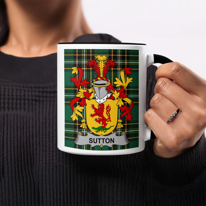 White mug with black handle featuring the Sutton family crest on a tartan background.