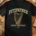 Fitzpatrick Irish harp T-shirt in Black, with cream surname lettering, a gold-toned harp, green shamrock and “Irish Heritage” text.