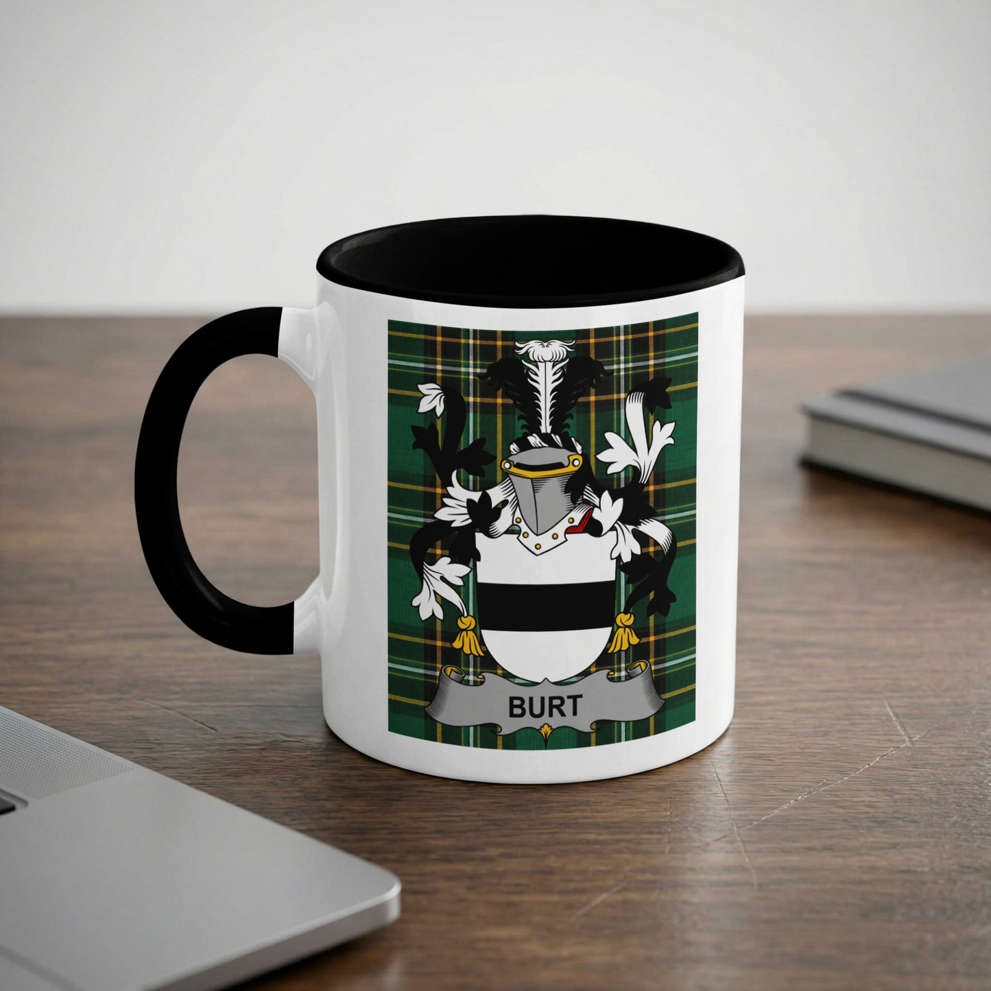 White mug with black rim and handle displaying a green plaid crest with the name BURT.
