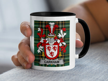 White mug with black rim, featuring a red and white family crest and tartan pattern.