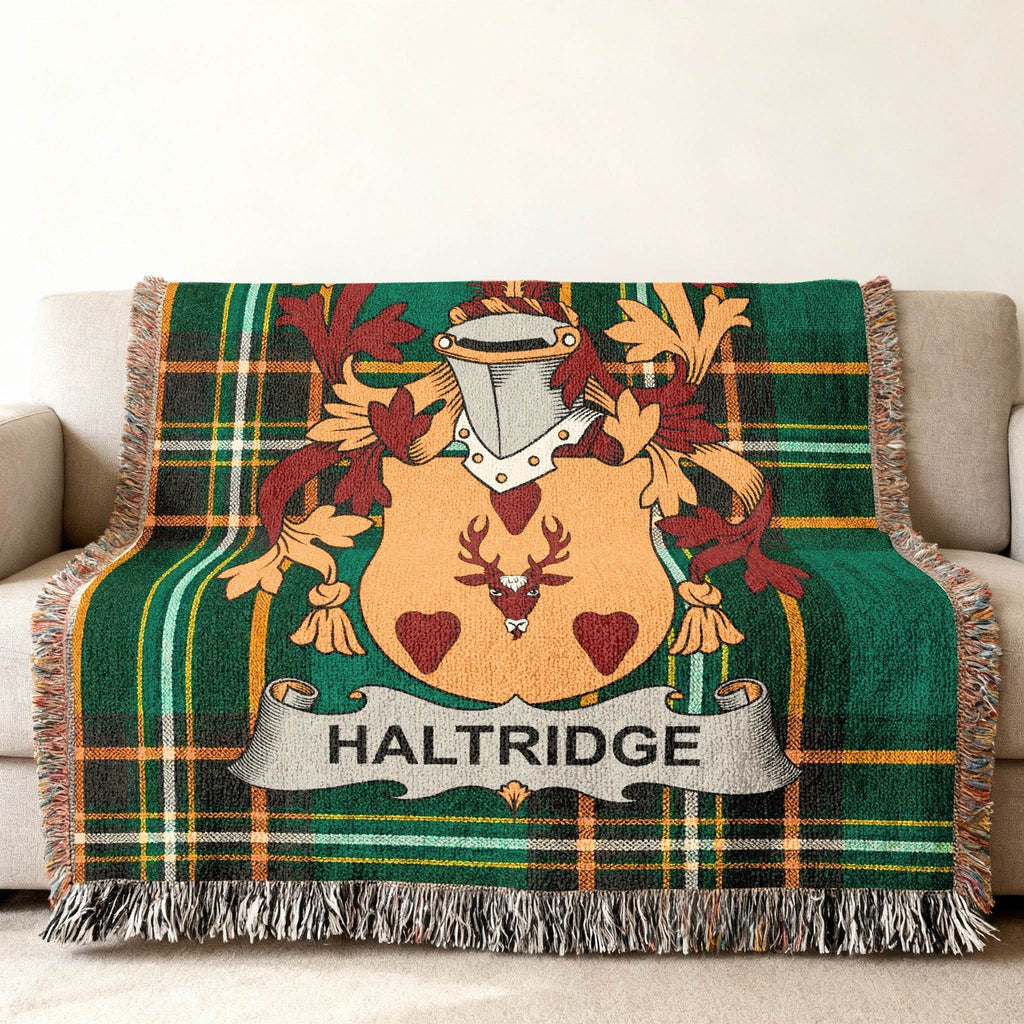 Haldridge family crest on a green tartan throw blanket on a sofa.