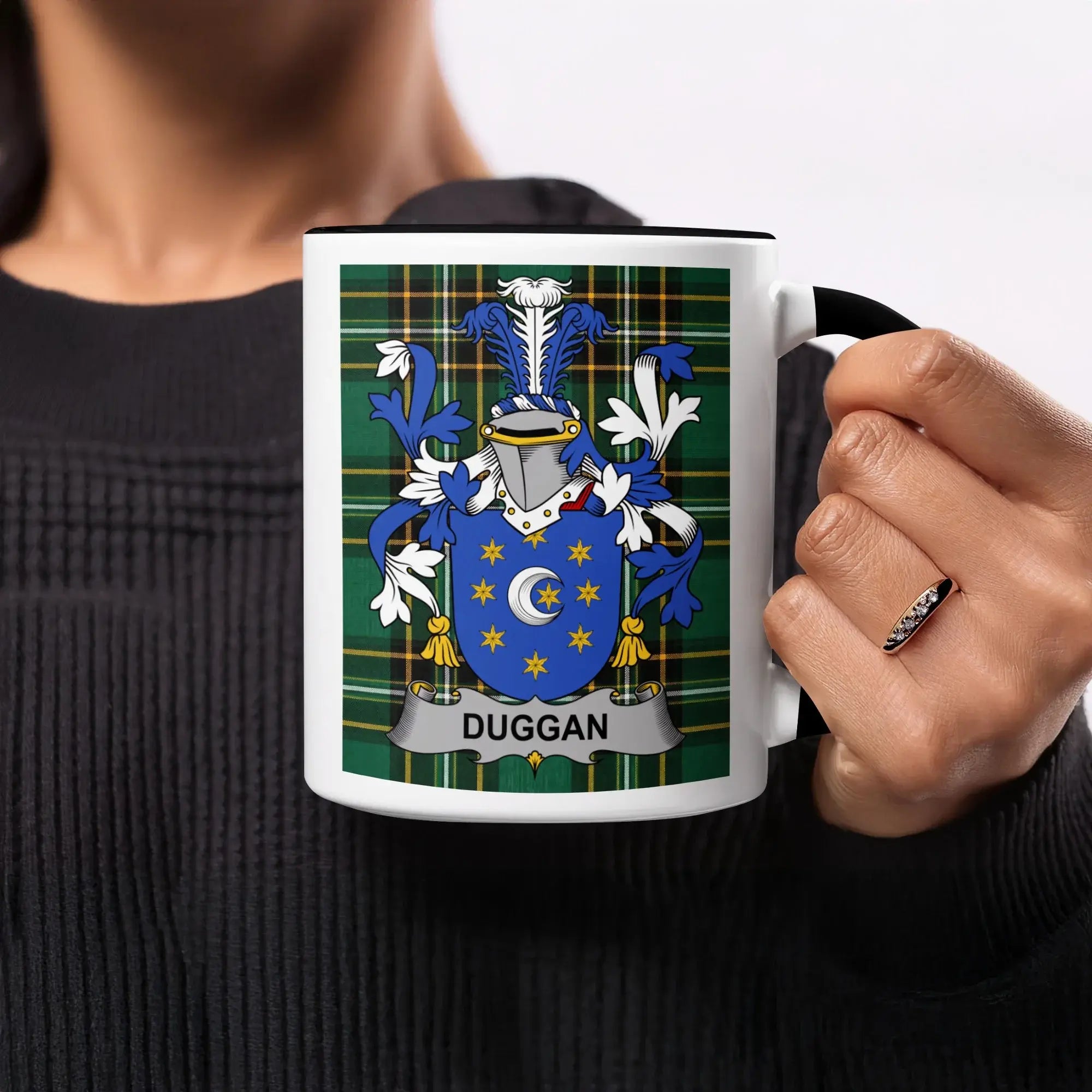 Black mug with Duggan family crest on plaid background.