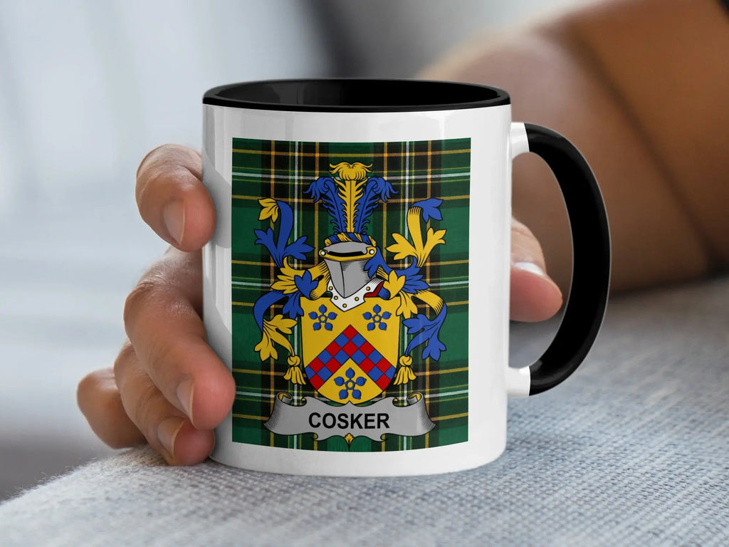 White mug with black rim displaying the Cosker family crest on a plaid background.