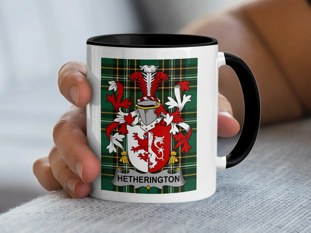 White mug with black rim displaying Hetherington coat of arms on plaid background.