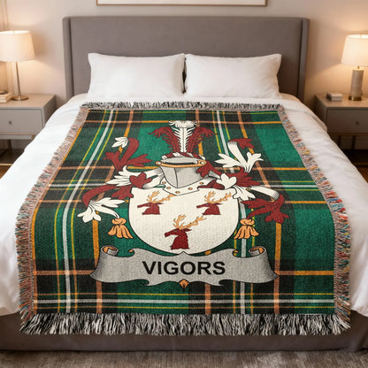 Tartan blanket with VIGORS family crest, spread on a bed.