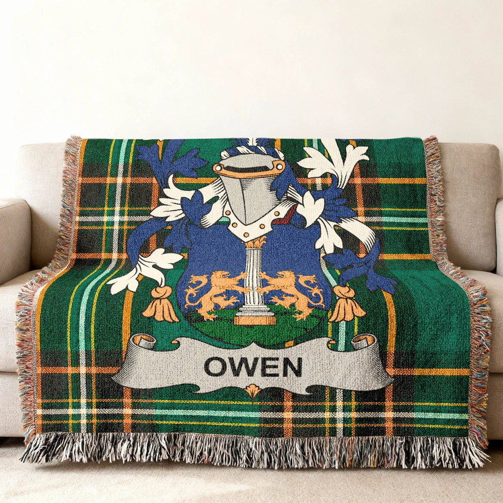 Green tartan plaid blanket with "OWEN" family crest on a sofa.