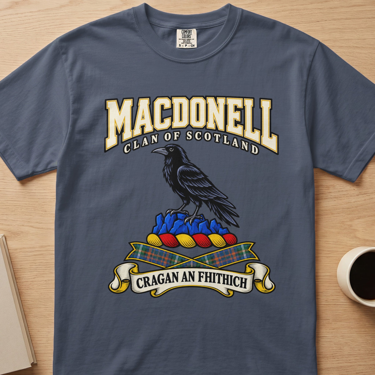 MacDonell dark bird perched on blue rocks graphic on a slate blue Comfort Colors T-shirt, front view