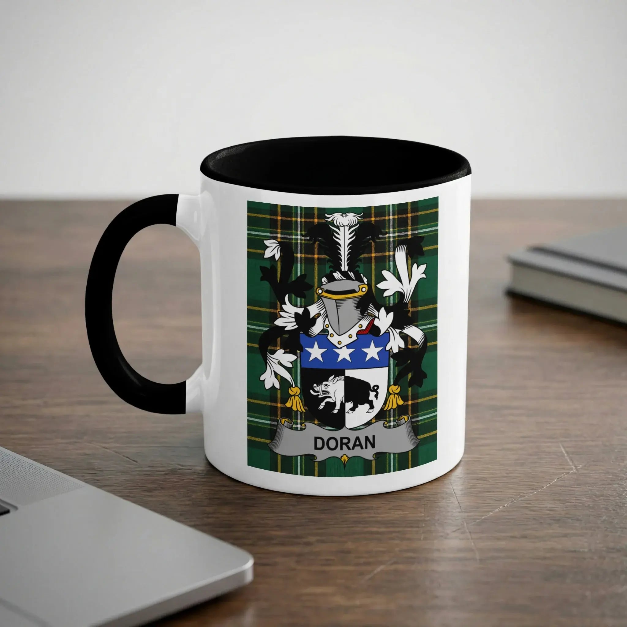 White mug with black rim and handle featuring Doran family crest on green plaid background.