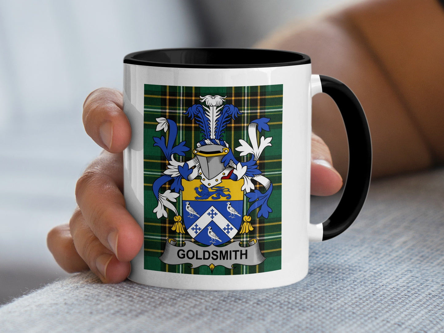Mug with crest and "Goldsmith" text held by a hand.