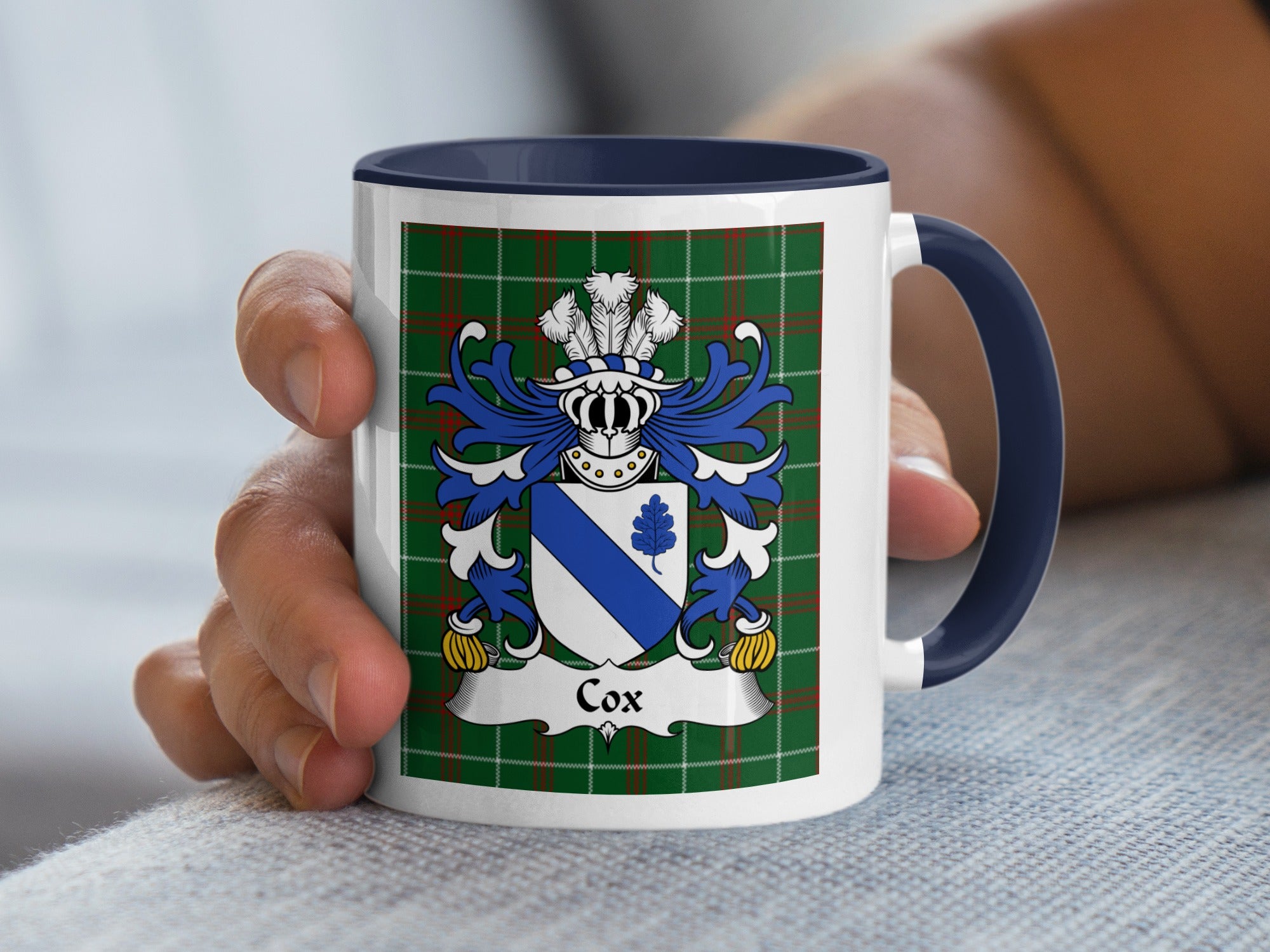 White mug with navy handle and interior, featuring Cox family crest on green tartan background.