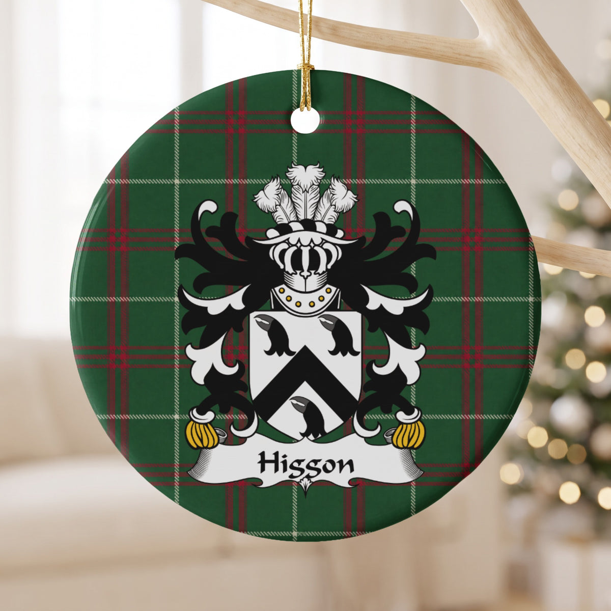 Higgon ornament hanging from a pale wooden branch; three black bird heads and a black chevron on a white shield on Welsh national tartan.