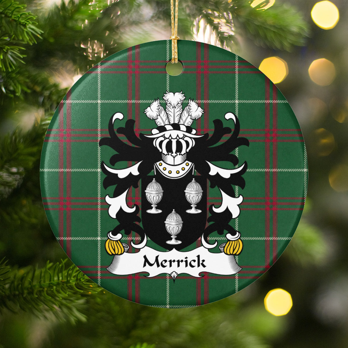 Merrick ornament hanging among Christmas tree branches and warm lights; three white covered cups on a black shield on Welsh national tartan.
