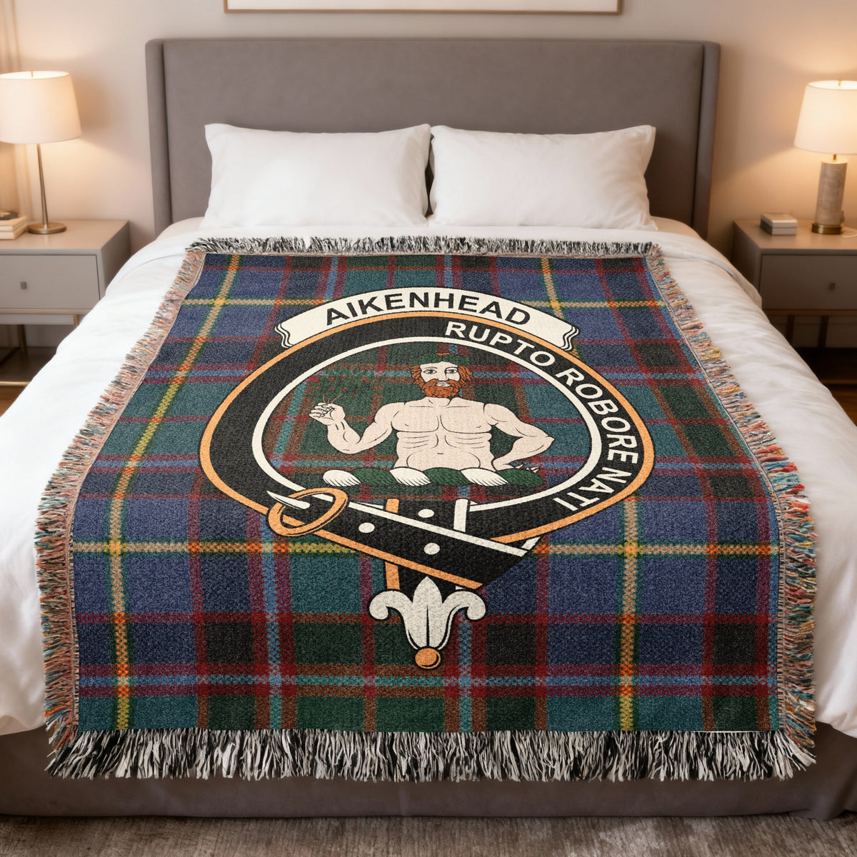 Aikenhead woven blanket displayed on a bed, with a bearded figure holding a branch on a green, blue and red tartan background