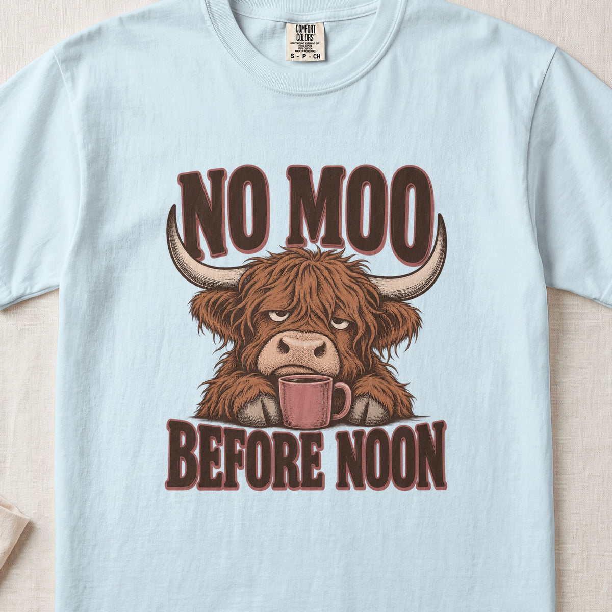 No Moo Before Noon Highland cow design on a Chambray Comfort Colors 1717 T-shirt, flat lay