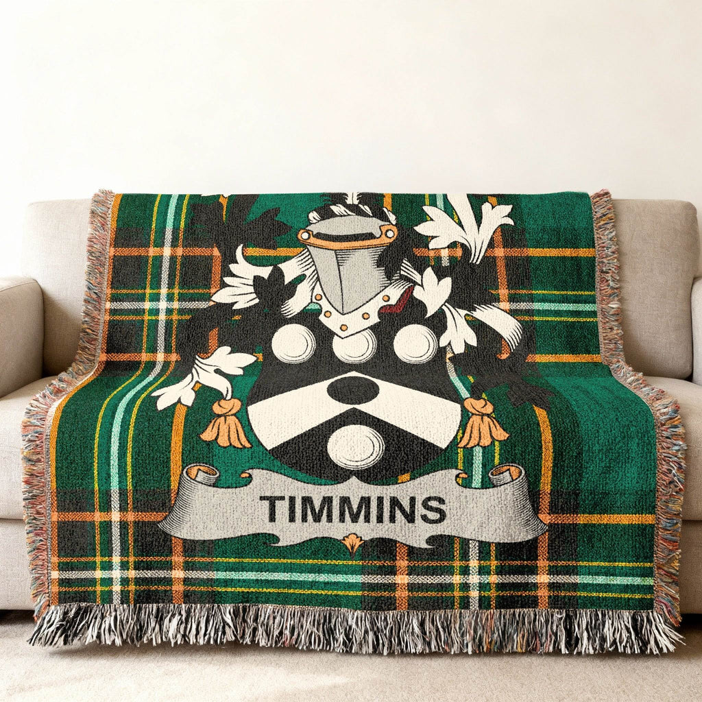 Green tartan throw blanket with Timmins family crest on a sofa.