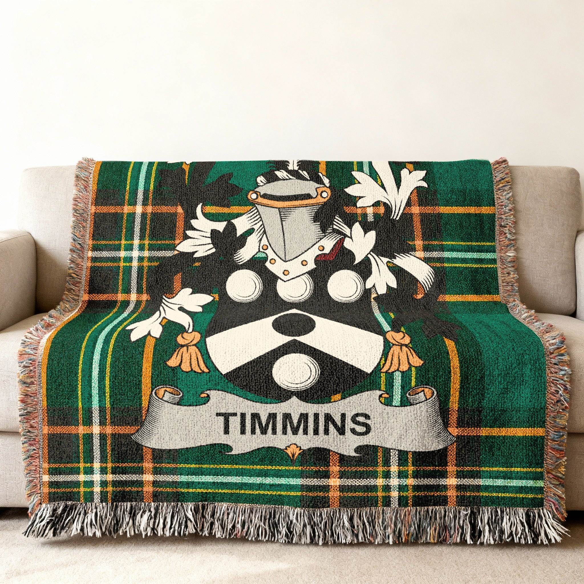 Green tartan throw blanket with Timmins family crest on a sofa.