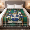Tartan blanket with Usher coat of arms draped on a bed.