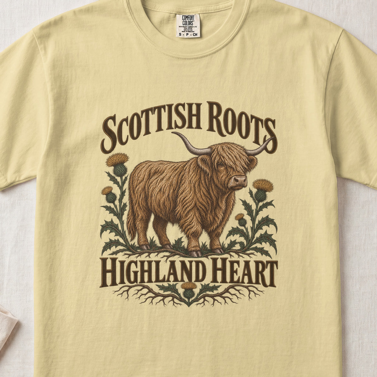 Scottish Roots, Highland Heart Highland cow design on a Butter Comfort Colors 1717 T-shirt, flat lay