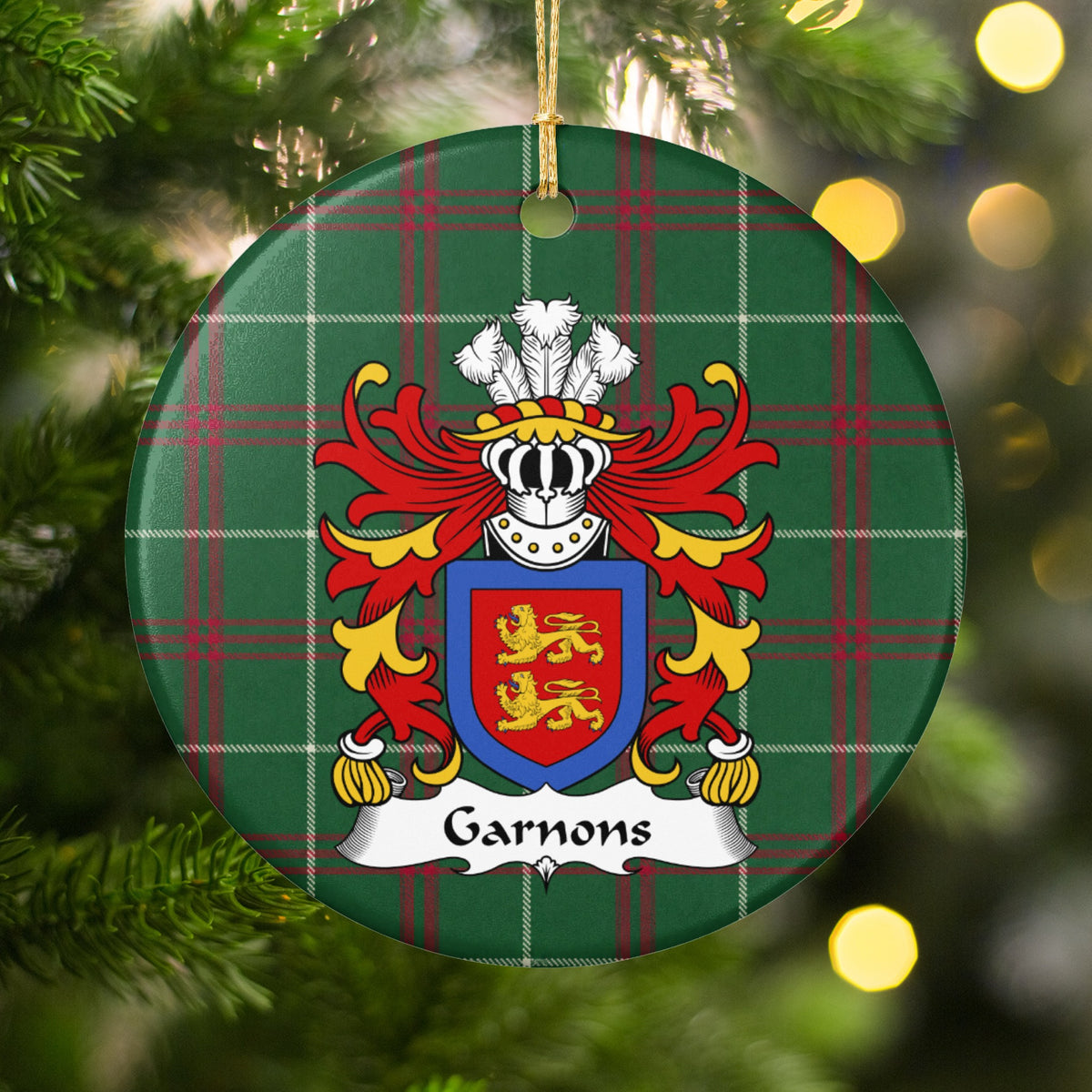 Garnons ornament hanging among Christmas tree branches and warm lights; two gold lions on a red shield enclosed by a blue border on Welsh national tartan.