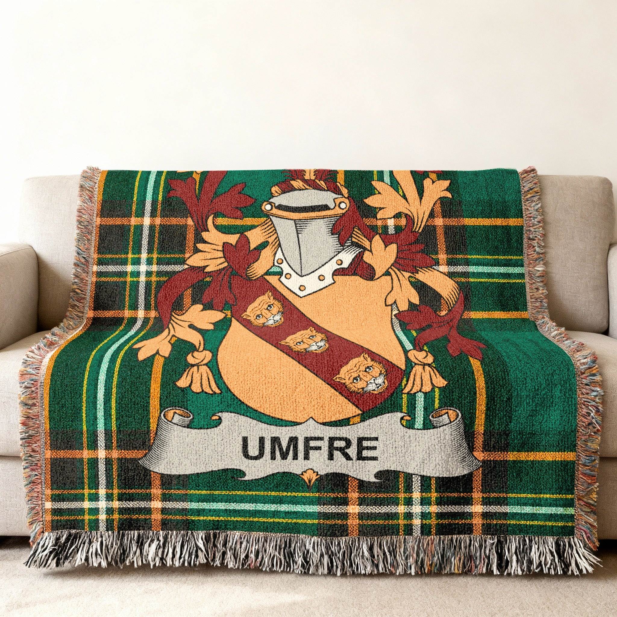Woven tartan blanket with the UMFRÉ crest, draped on a sofa.