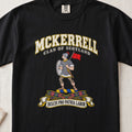McKerrell Scottish clan T-shirt in Black, front view with an armoured figure carrying a shield and red flag and motto banner.