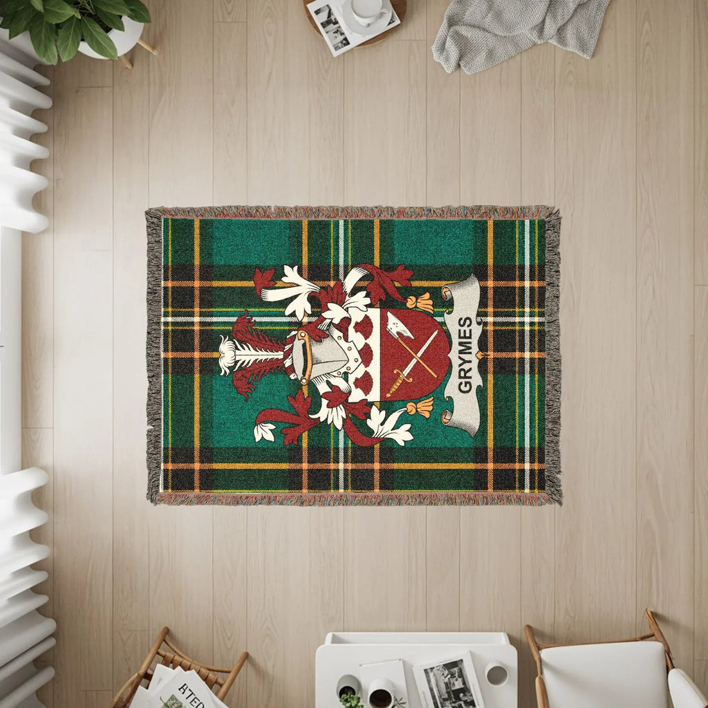 Green tartan blanket with GRYMES crest, draped on a wooden floor.