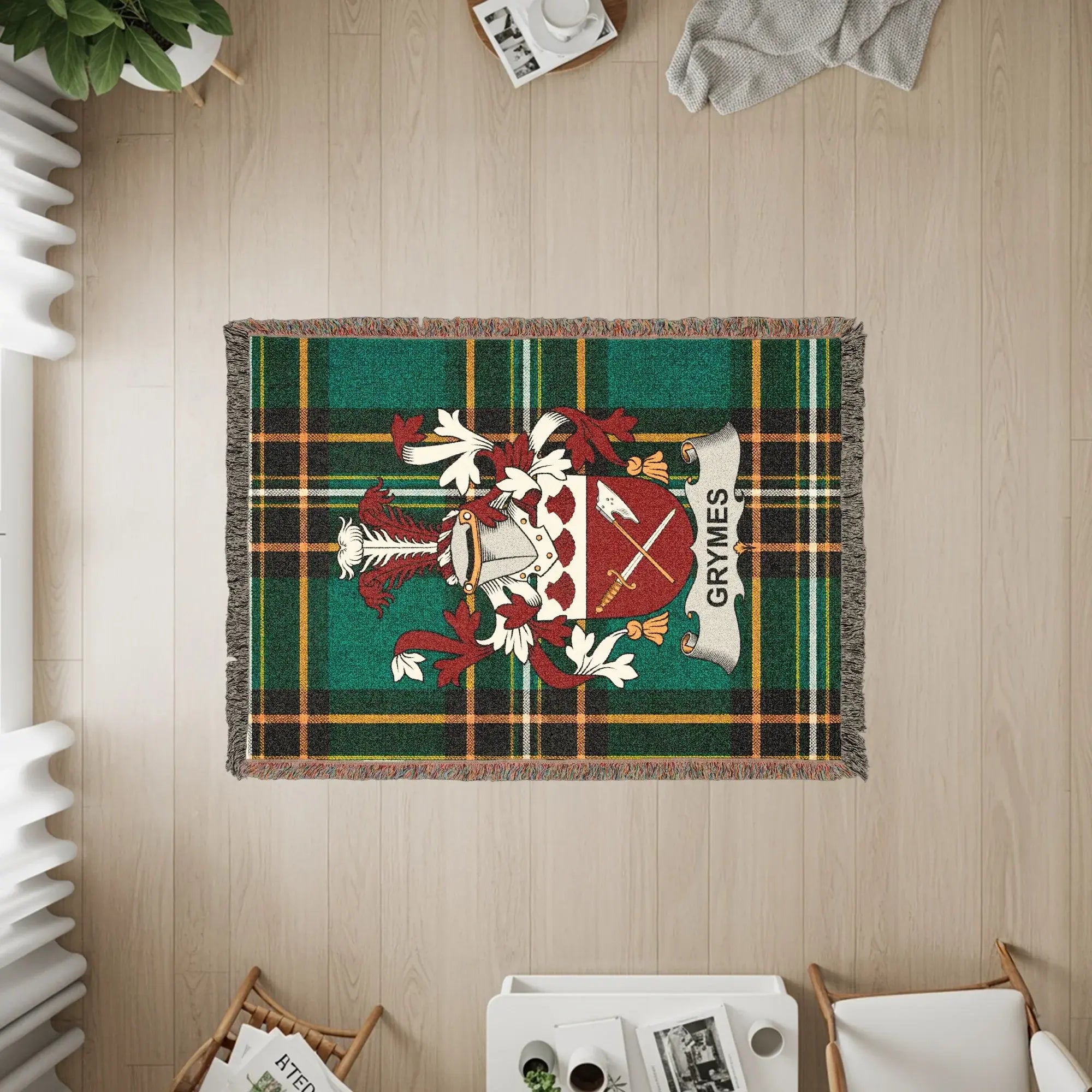 Green tartan blanket with GRYMES crest, draped on a wooden floor.