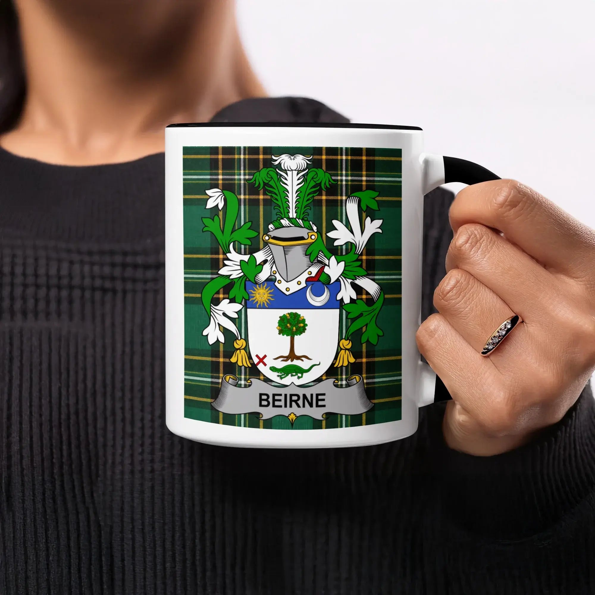Beirne family crest on white mug with black rim, held by a person.
