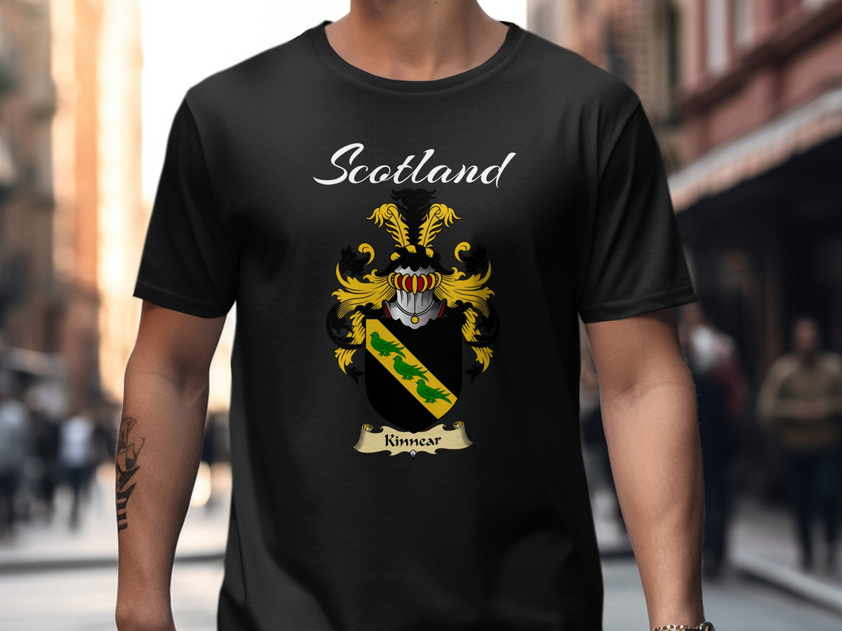 Model wearing a black Kinnear T-shirt featuring a gold diagonal band with green leaves on black