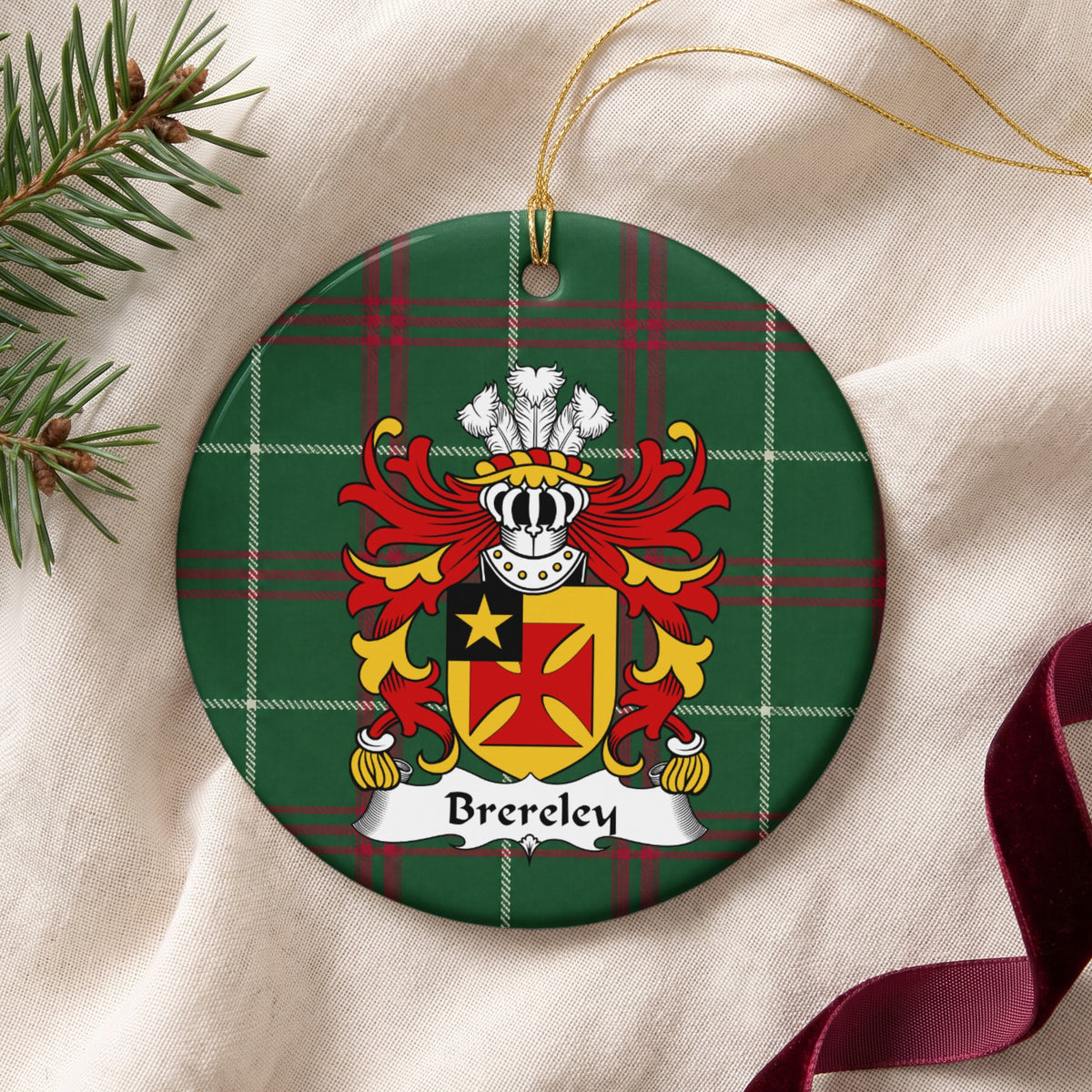 Brereley ornament on cream fabric with gold string, evergreen and burgundy ribbon; a red flared cross on gold with a gold star in a black corner panel on Welsh national tartan.